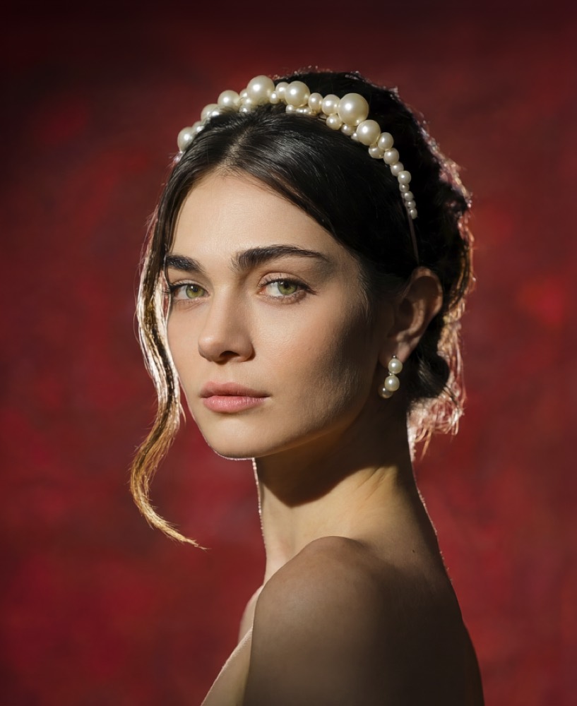 Retrato de estudio de una novia con tocado de perlas sobre fondo rojo